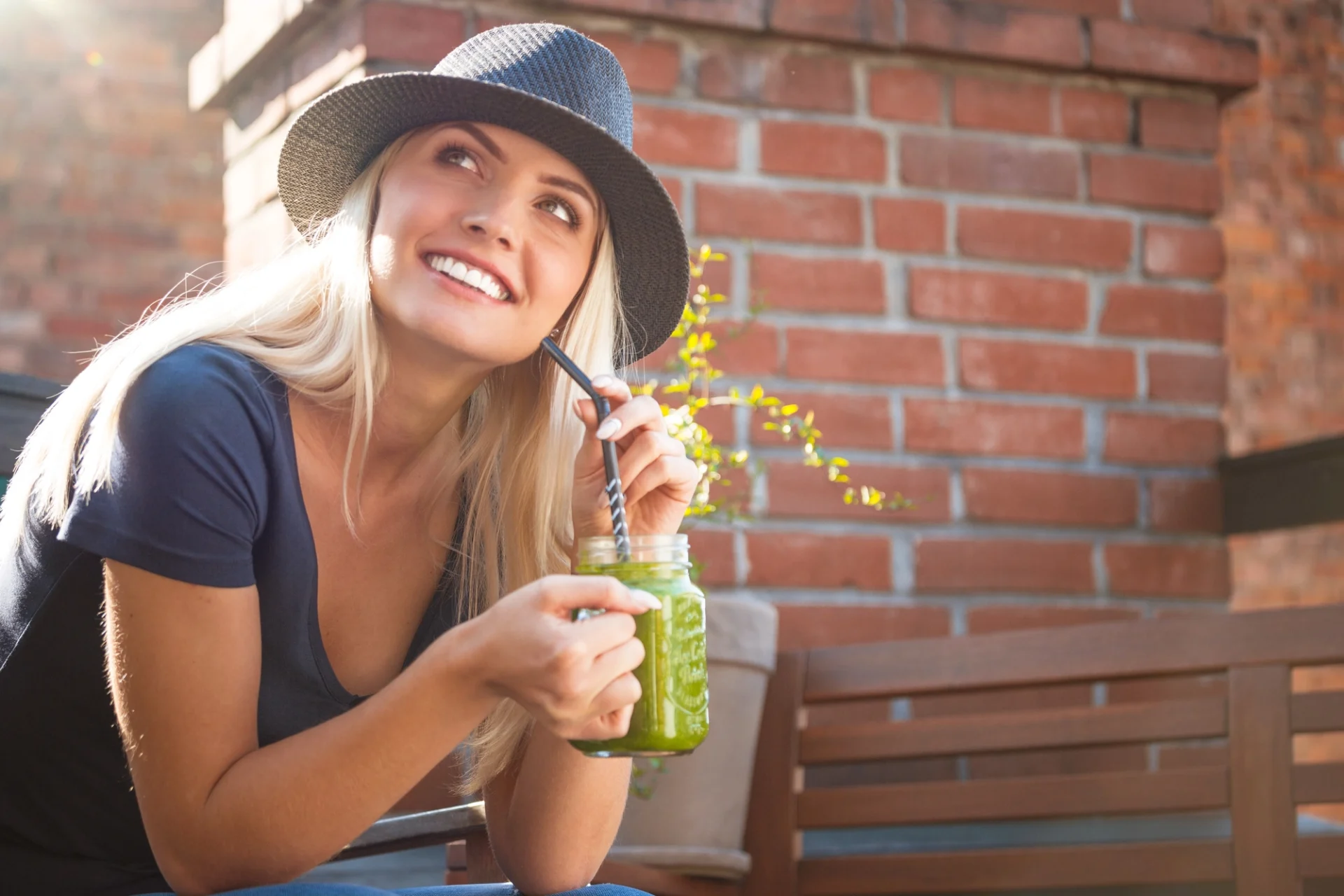 happy young blonde woman drinking a green smoothie