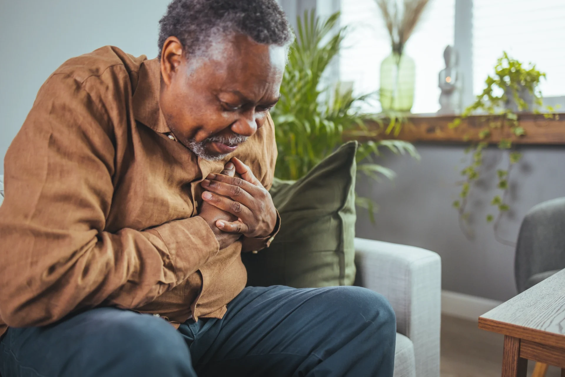 elderly African-American man holding chest as if in pain