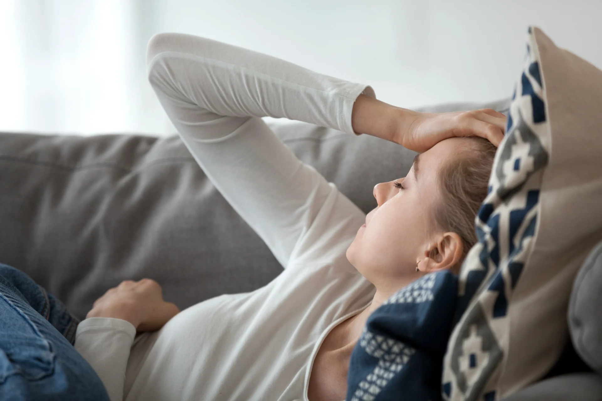 woman lying on the couch with eyes closed and hand over her forehead