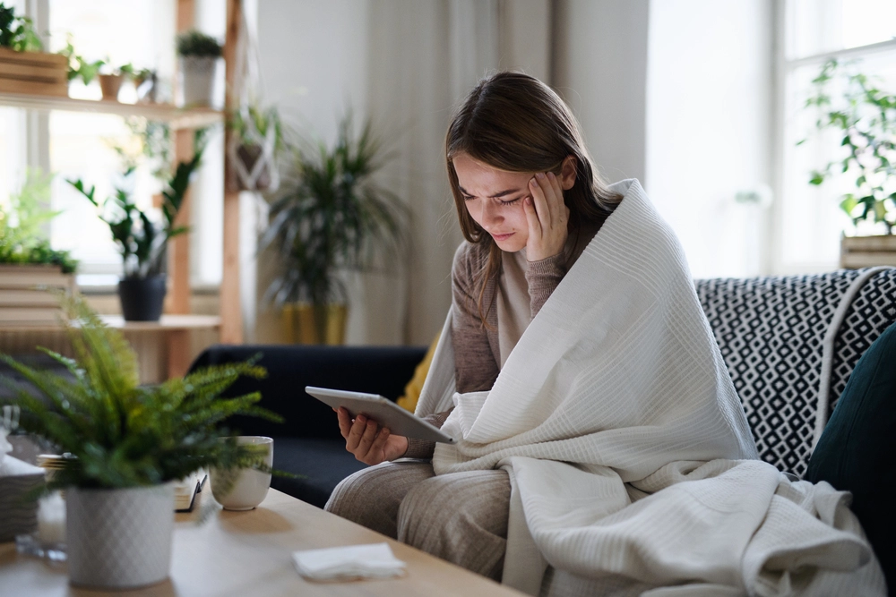 picture of a frustrated woman wrapped in a blanket looking at tablet