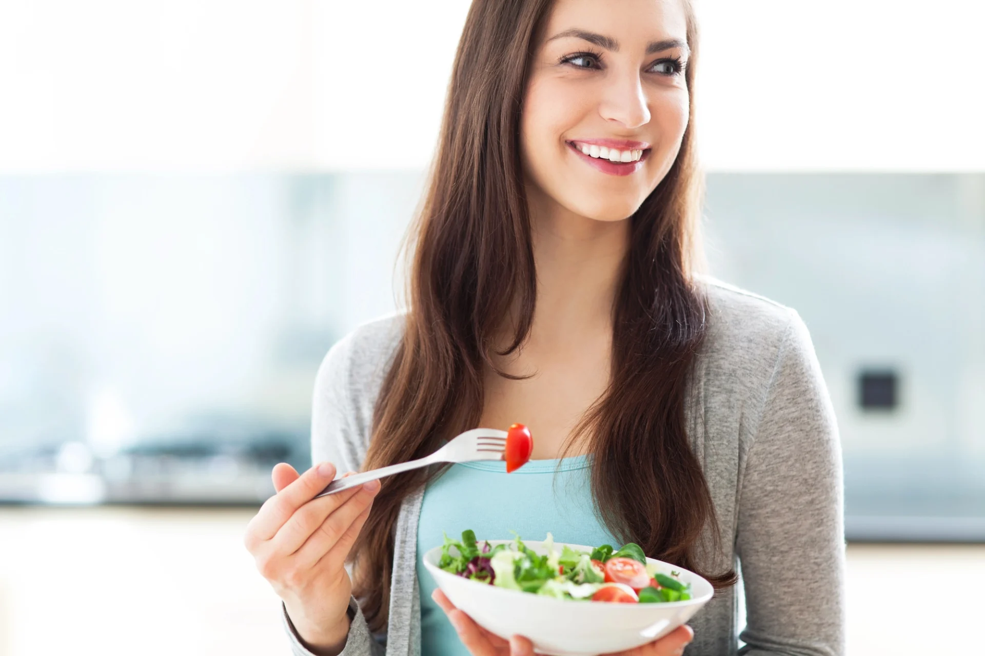 pretty young woman smiling and eating a salad