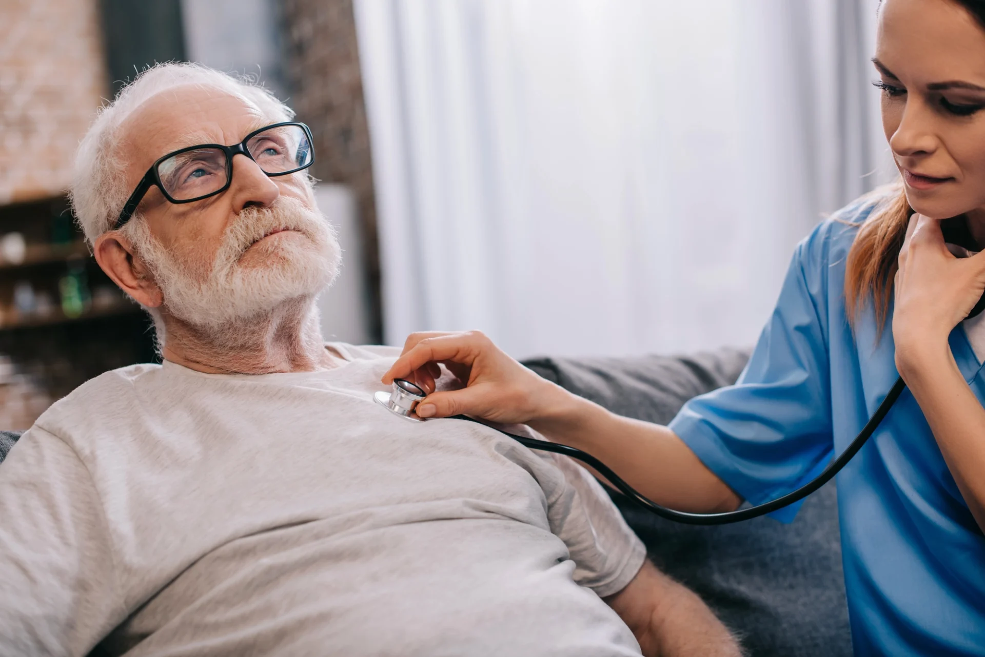 female nurse listening to elderly man's heart through a stethoscope