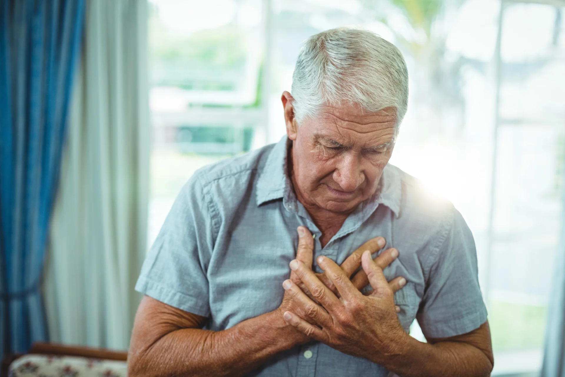 elderly man clutching his chest with both hands