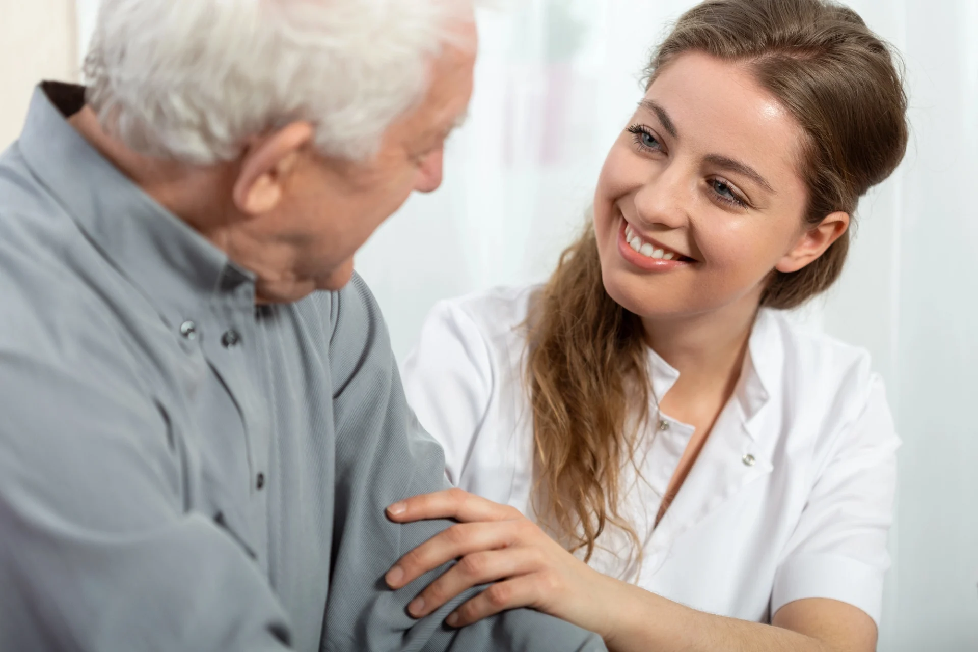 young woman smiling at an elderly man with her hand on his arm