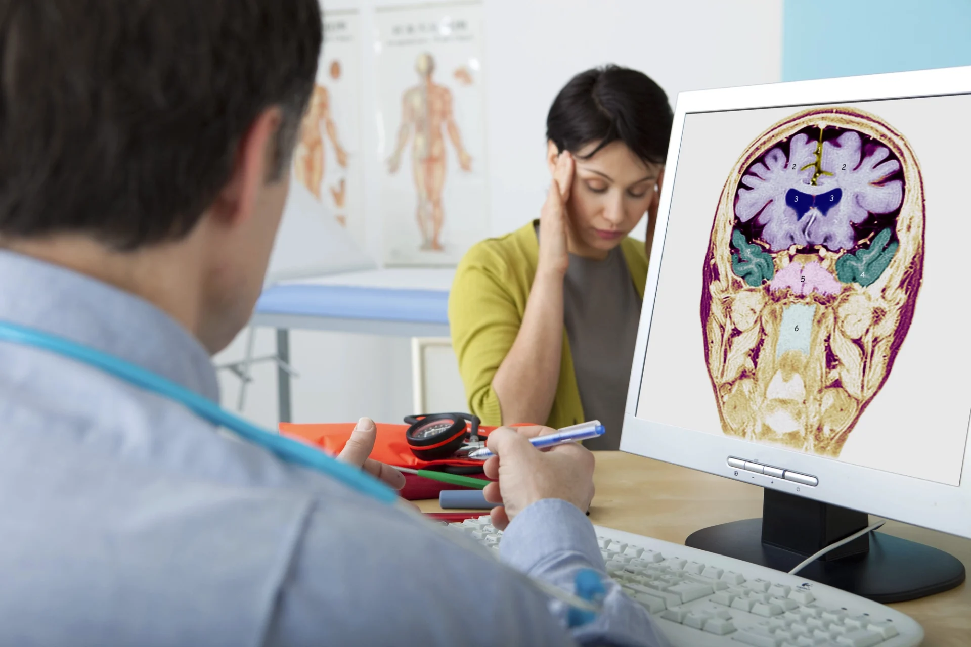 doctor talking to a distraught looking patient with a photo of a brain on his his monitor