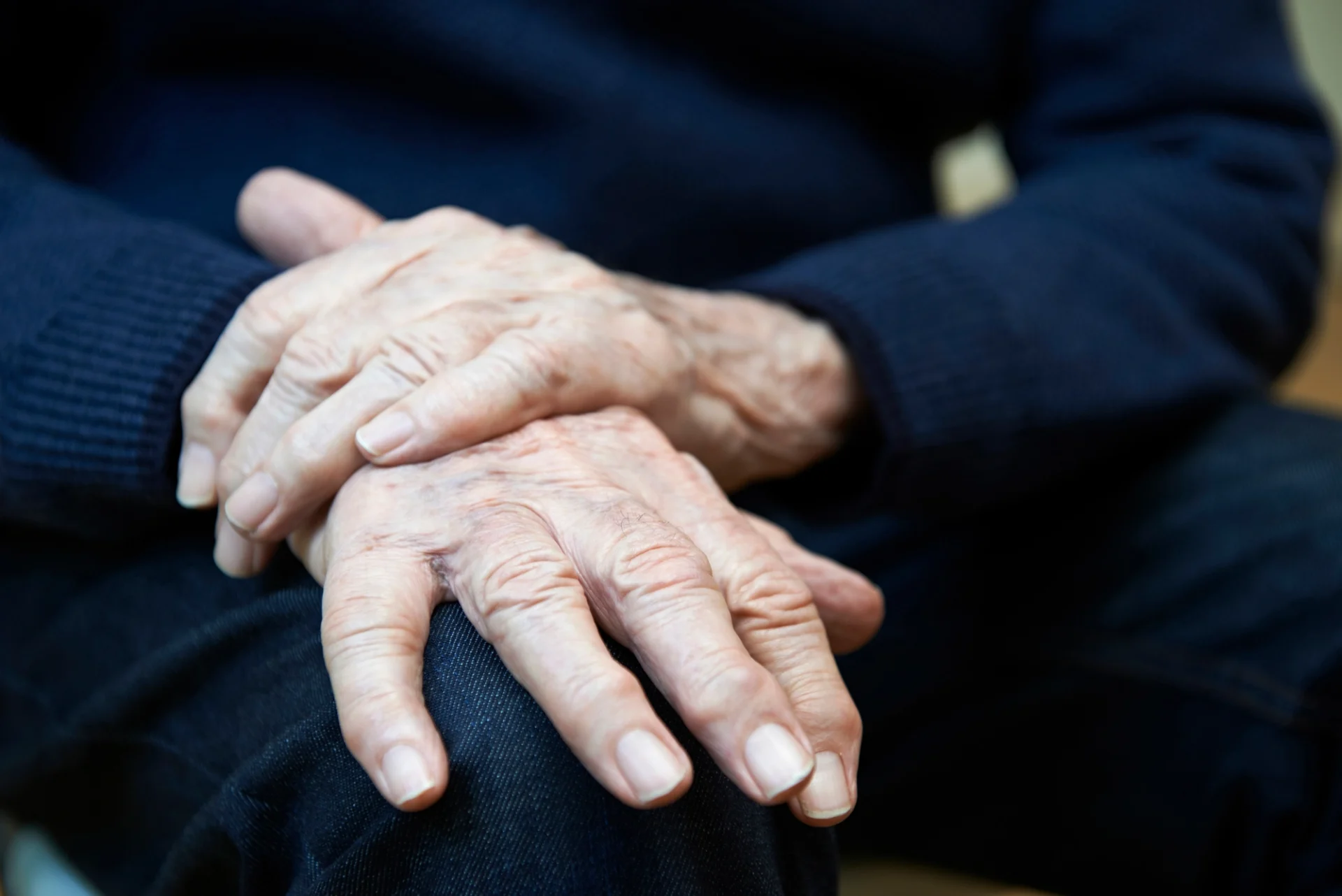 close up of elderly man's hands, one hand over the other as if trying to calm tremors