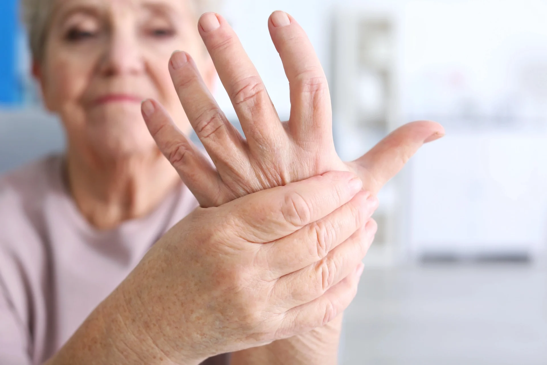 close up of elderly woman holding her hand as if in pain from arthritis