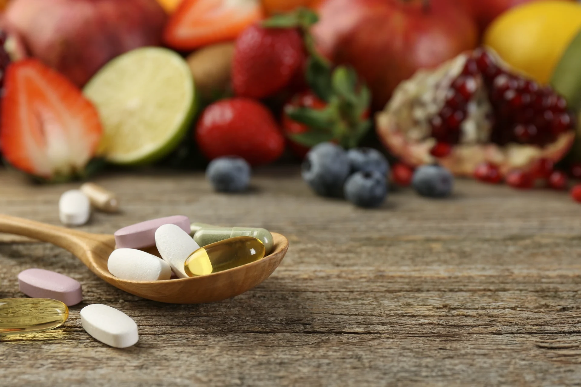 supplements with fruit in background on wood table