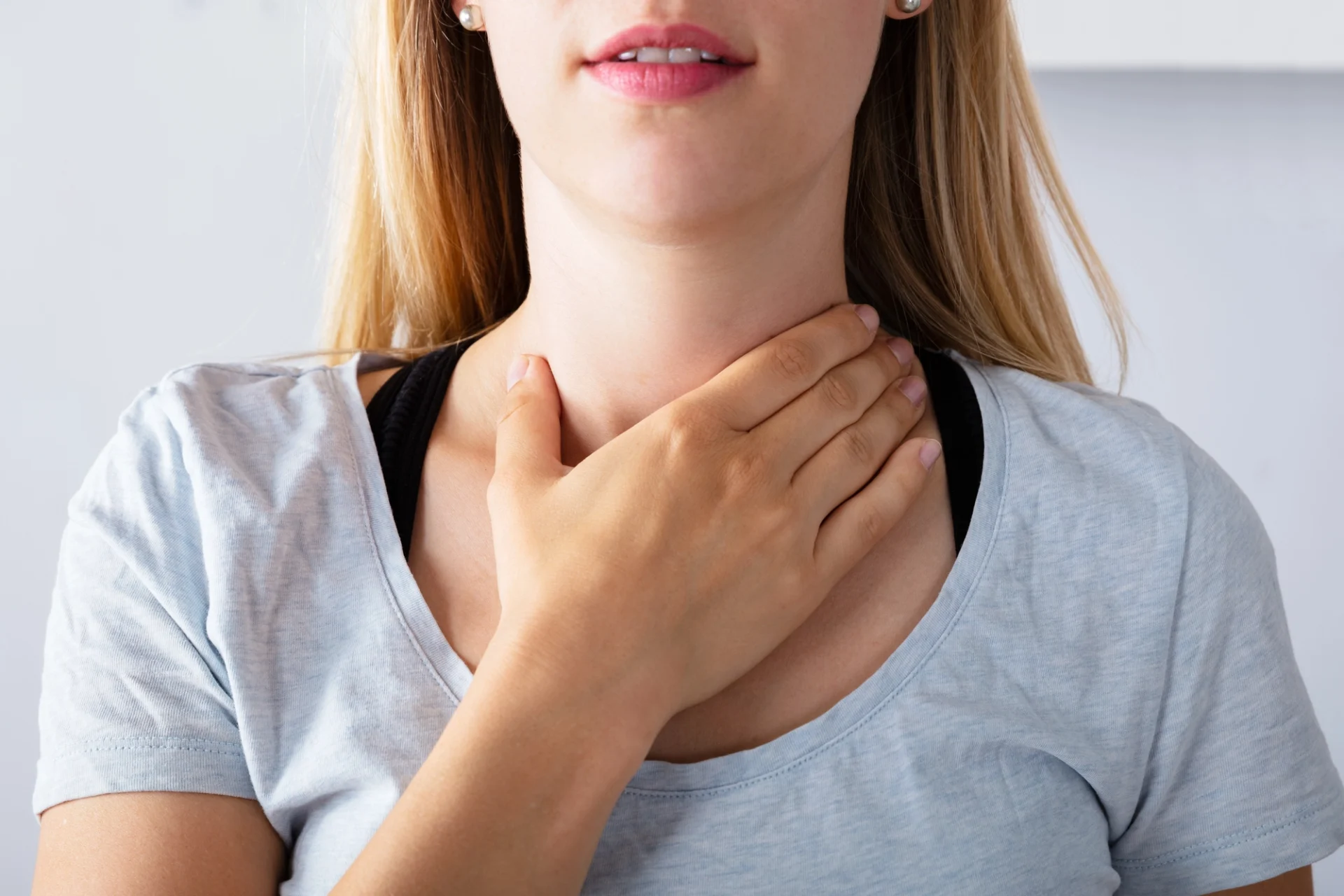 close up of woman with hand over her neck